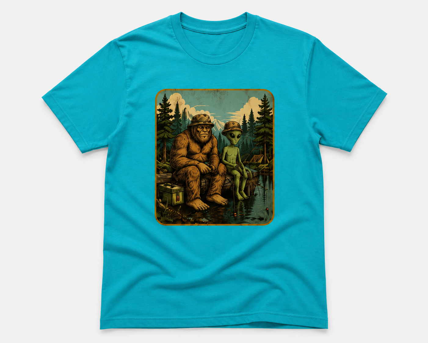 A bright turquoise blue short-sleeve t-shirt with a rectangular vintage-style graphic print on the chest showing a Bigfoot and an alien sitting by a lake in a forest.