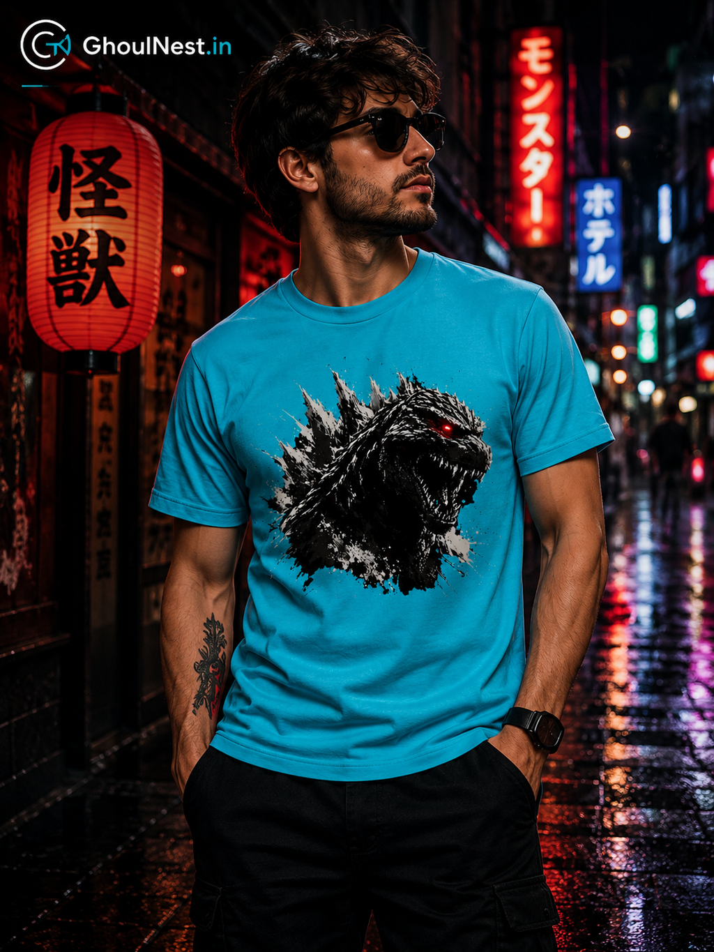 A man wearing a bright blue t-shirt with a Godzilla graphic print, standing on a wet city street at night with neon lights and Japanese lanterns in the background.
