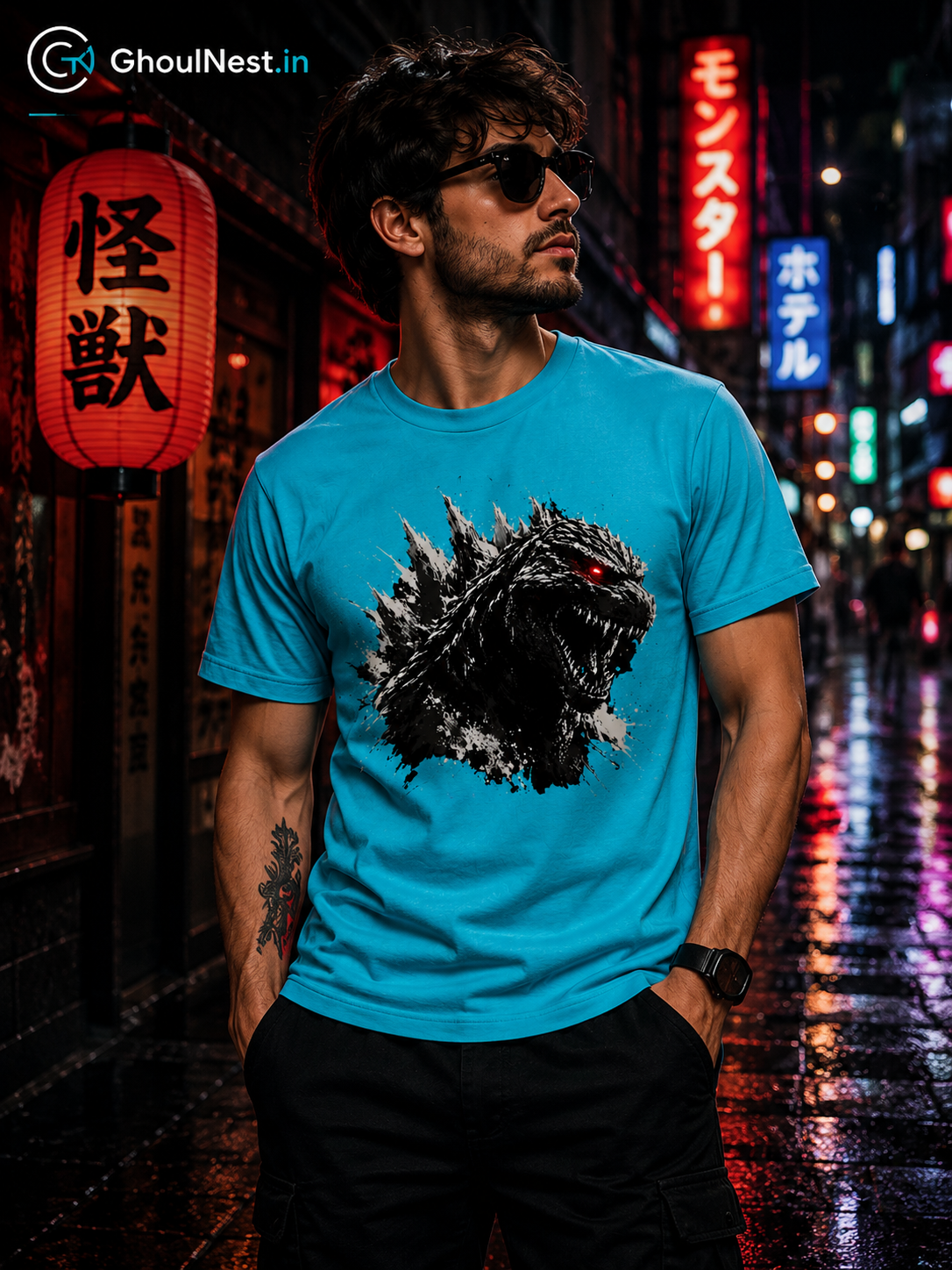 A man wearing a bright blue t-shirt with a Godzilla graphic print, standing on a wet city street at night with neon lights and Japanese lanterns in the background.